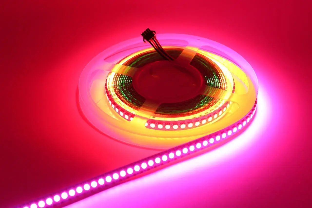 A coiled LED strip glowing with vibrant pink and red light on a flat surface.